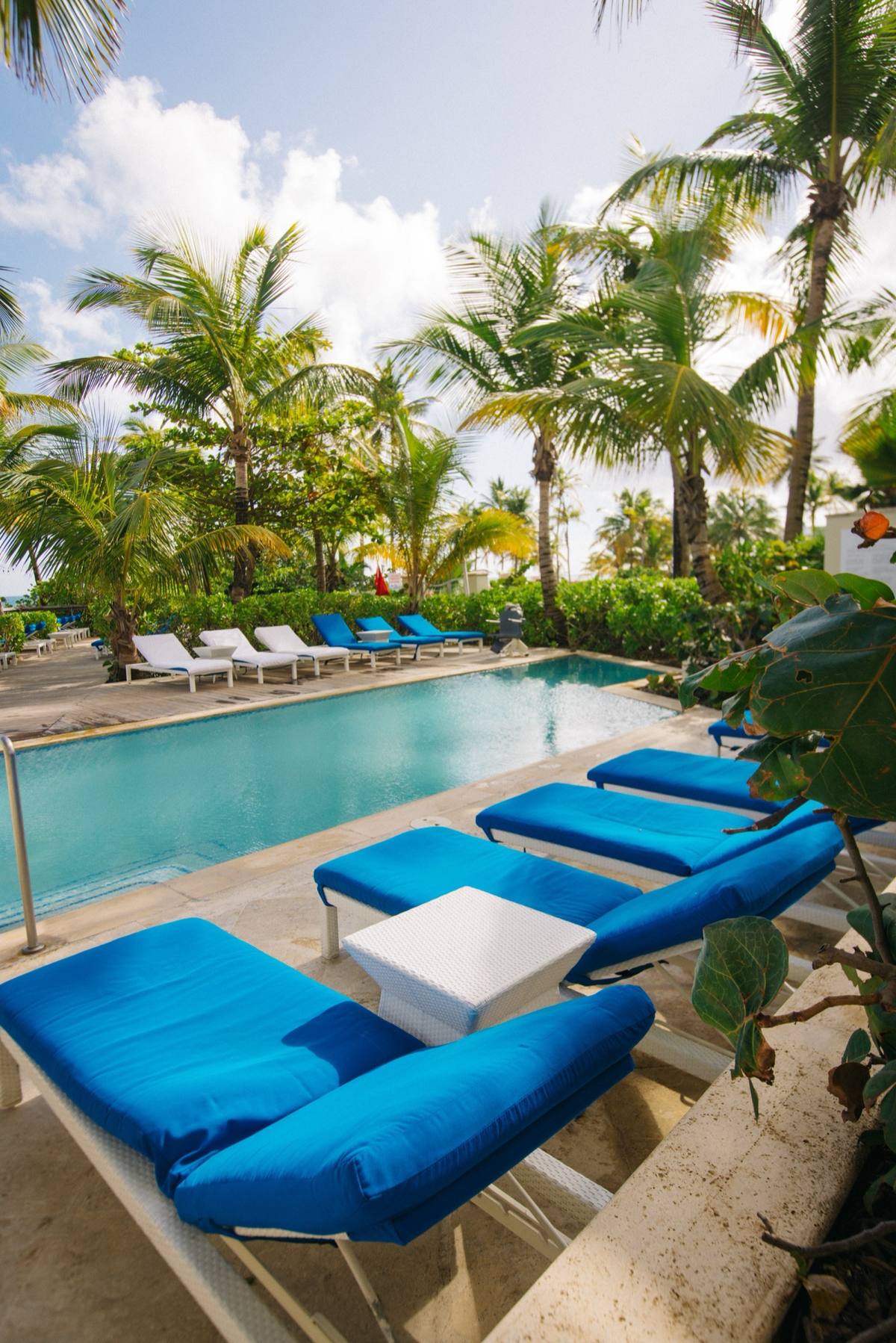 Detail shot of poolside lounge chairs and palm shadows at a Caribbean resort
