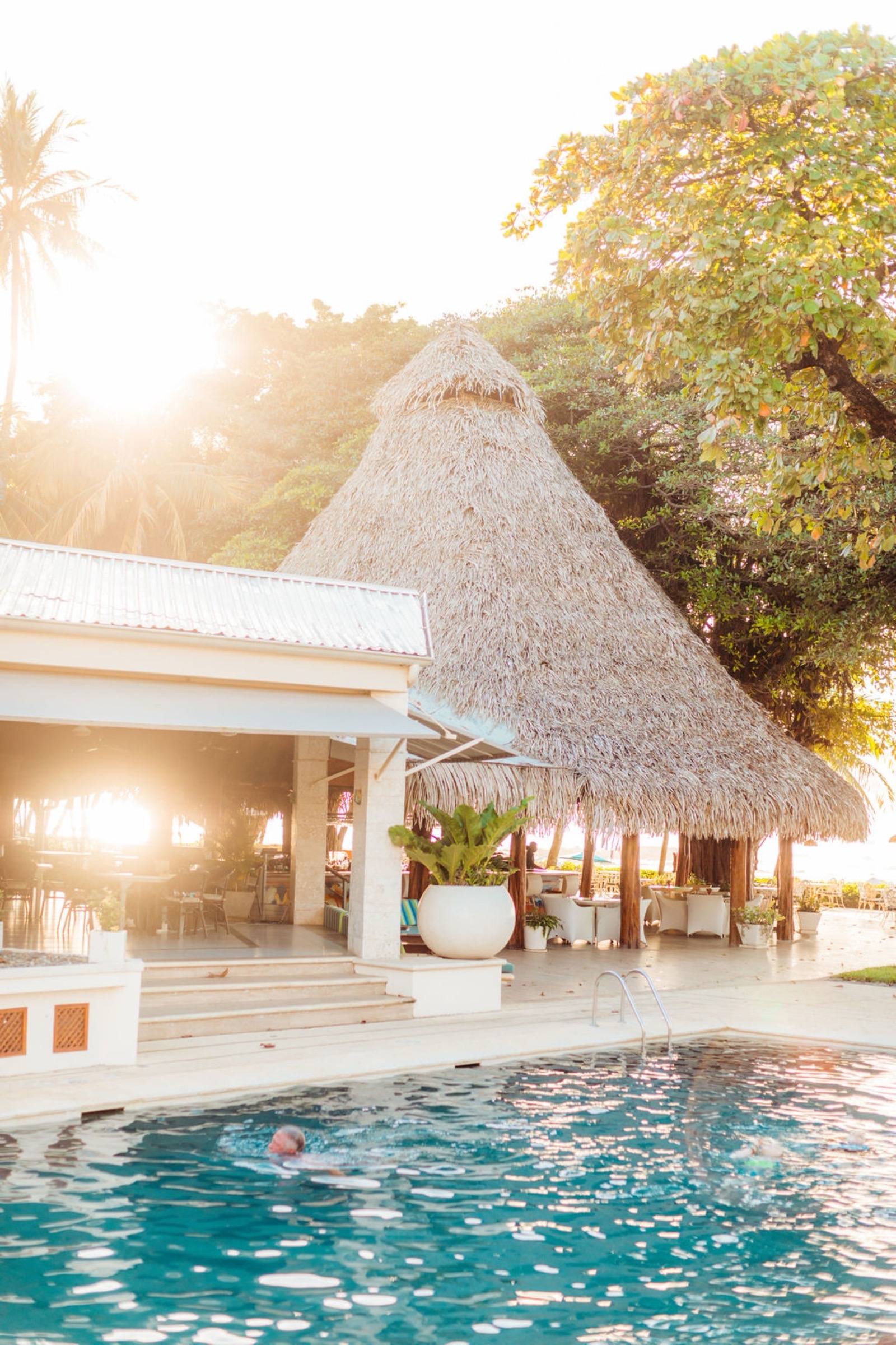 Beachfront resort pool and thatched-roof restaurant at golden hour in Costa Rica