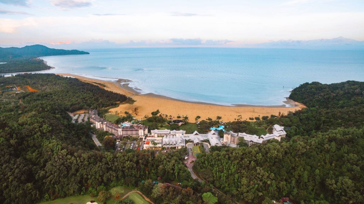 Aerial view of a beachfront resort framed by rainforest and coastline