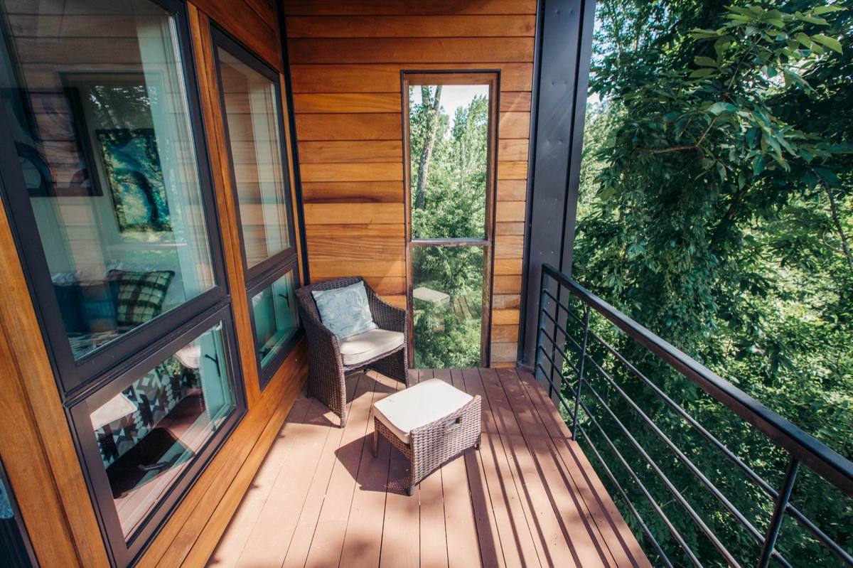 Private balcony deck of a treehouse-style accommodation surrounded by forest canopy