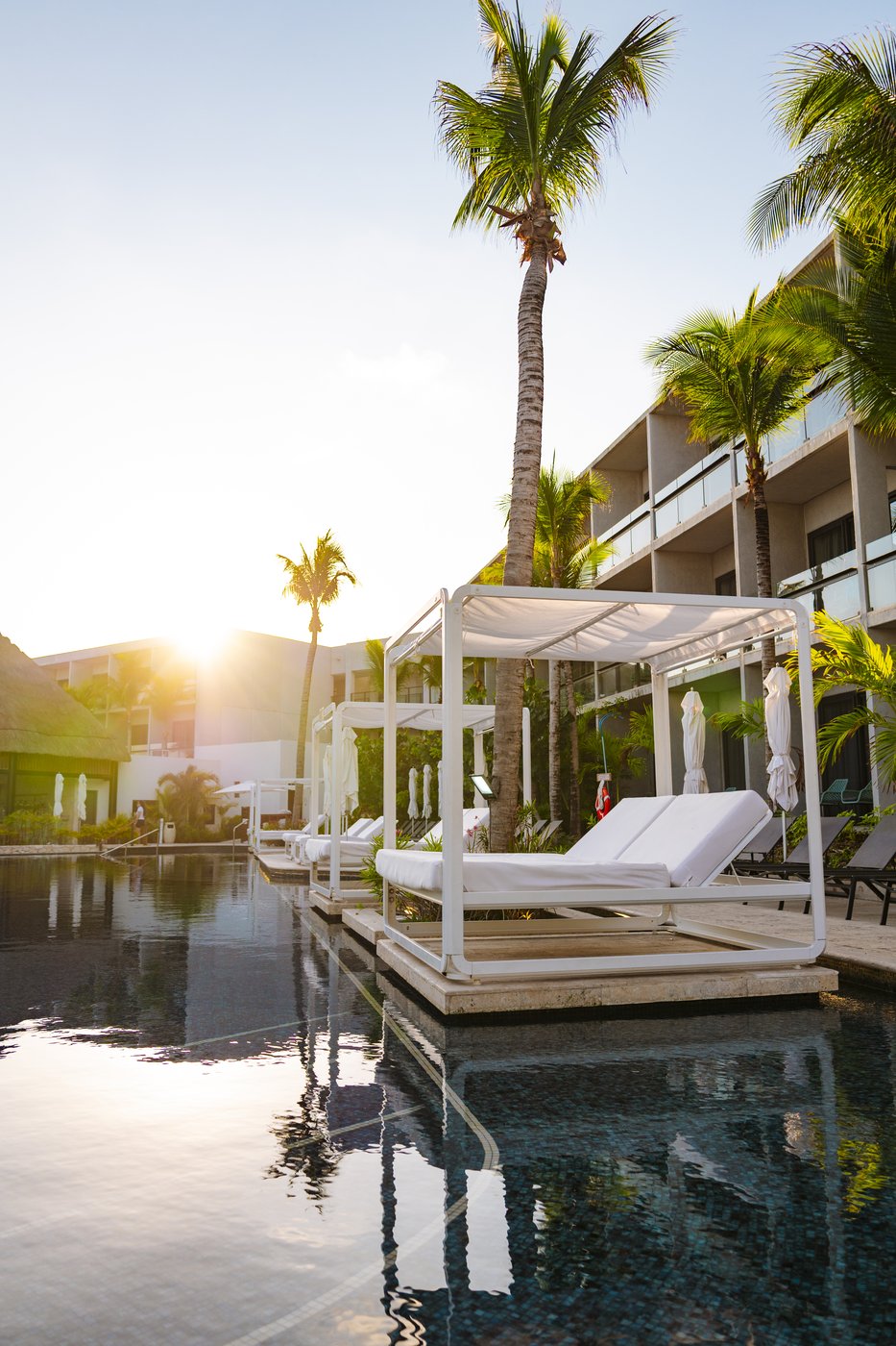 Rooftop pool deck with lounge chairs and a fire feature at dusk