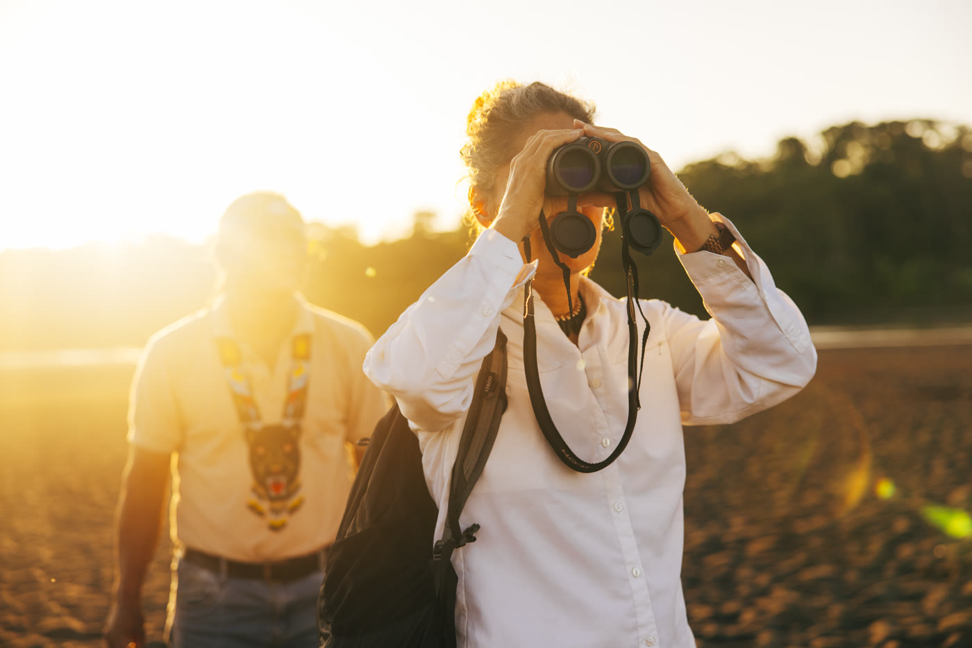 Guest birdwatching with binoculars alongside an Amazon expedition guide
