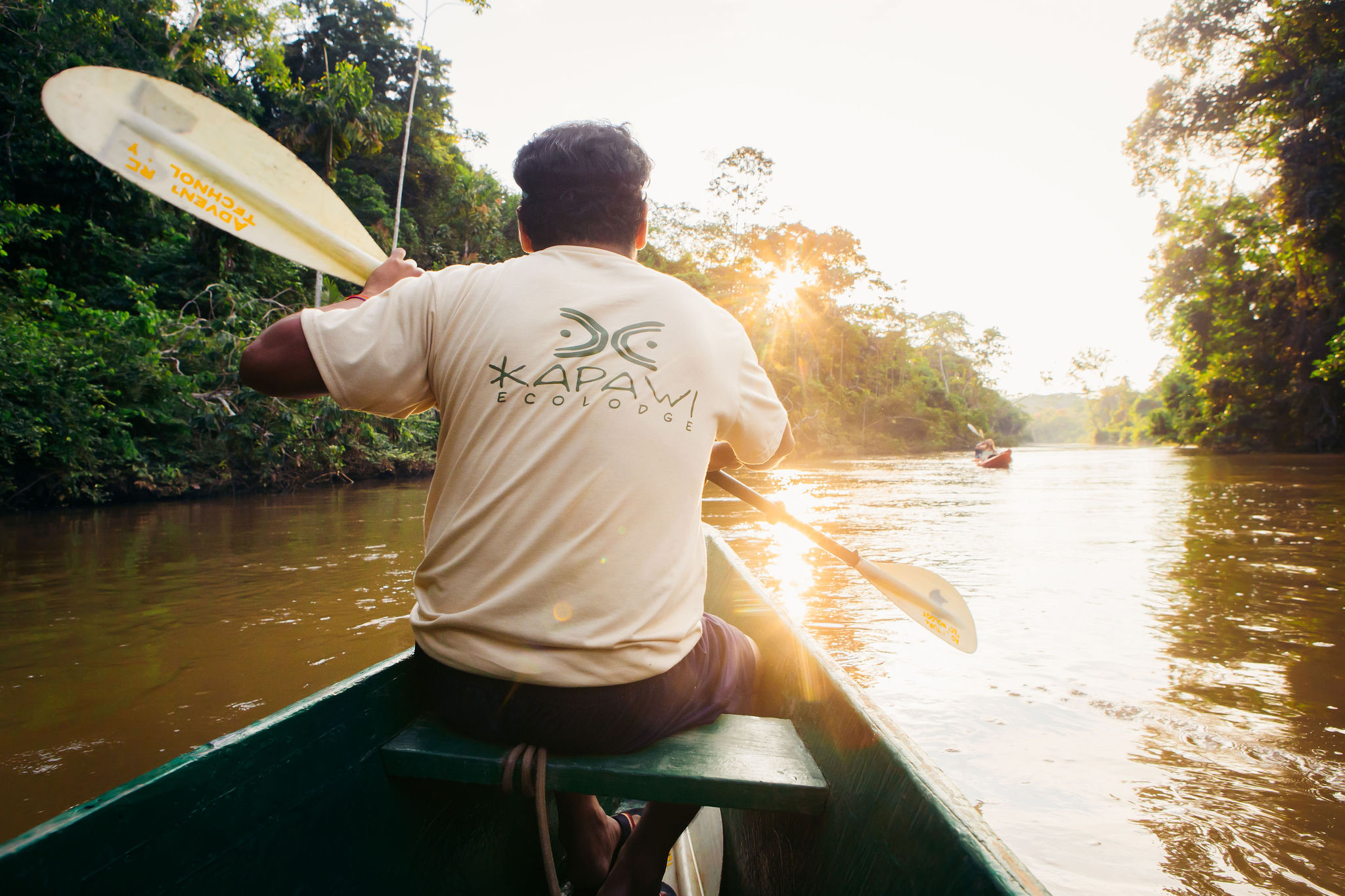 Guide paddling a traditional canoe on the river at Kapawi Ecolodge