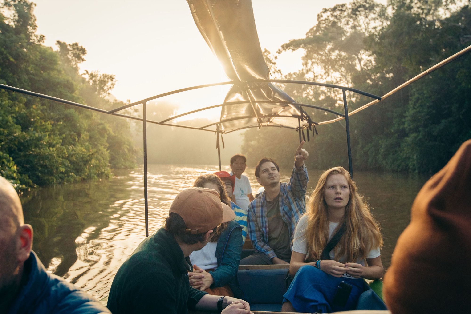 Guide leading a sunrise canoe tour through the Amazon with guests aboard