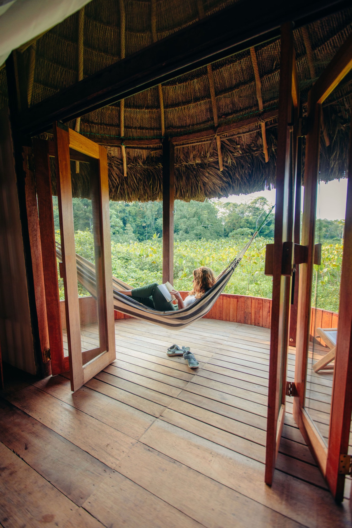 Guest reading in a hammock on an open-air deck at an Amazon ecolodge